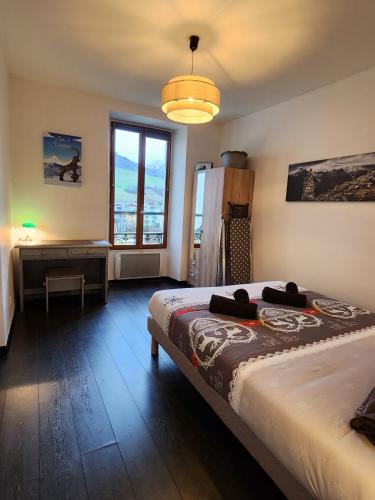 a bedroom with a bed and a desk and a window at le galeta cosy calme et chaleureux avec vue sur la montagne in Aigueblanche
