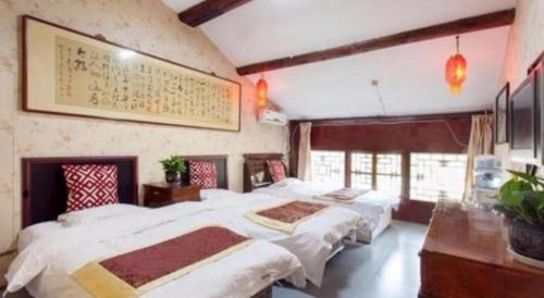 a bedroom with three beds and a painting on the wall at Pingyao Yufengheng Hotel in Pingyao