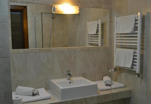 W łazience znajduje się umywalka, lustro i ręczniki. w obiekcie Casa de Oaspeți Sfântul Nicolae w Jassach