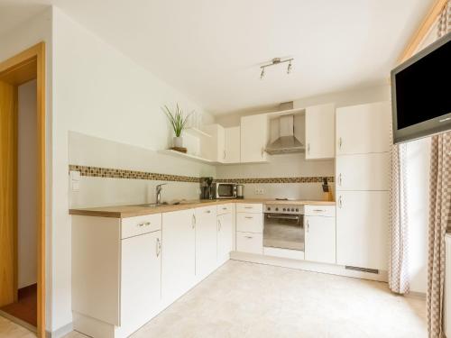 a white kitchen with white cabinets and a tv at Lovely Apartment in Hainzenberg next to Forest in Hainzenberg