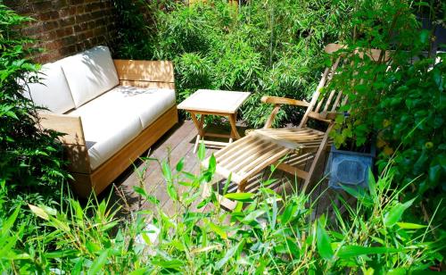 a couch and two chairs and a table in a garden at Villa du Square, Luxury Guest House in Paris