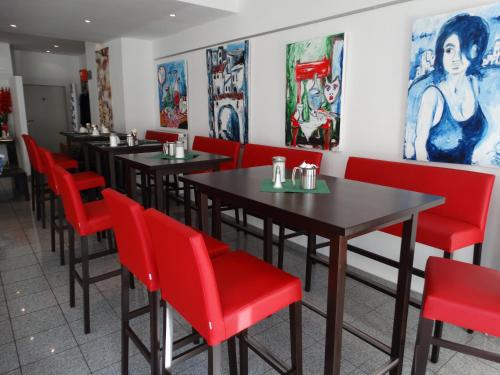 a row of tables and red chairs in a restaurant at Hotel Stay in Essen