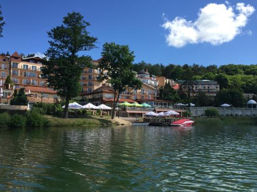a river with a red boat in front of a building at Panoramic-Oscar in Mrągowo