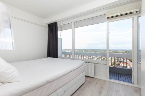 een slaapkamer met een bed en een groot raam bij Sea View Apartment in Zandvoort