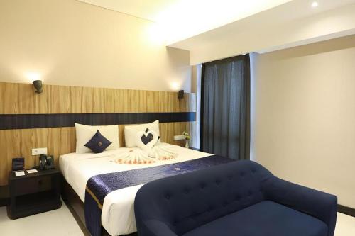 马贾伦卡Fitra Hotel Majalengka的一间卧室，里面有一张大床和一张蓝色沙发。