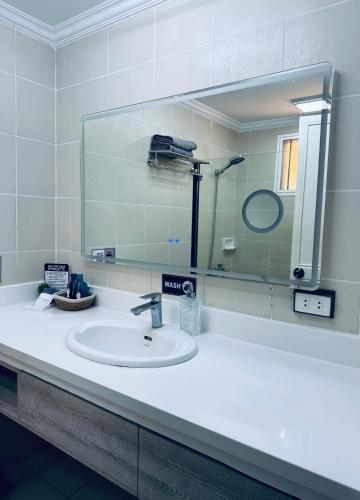 a bathroom with a sink and a large mirror at Club Balai Isabel - Audrey-Adam Staycation Balai in Batangas City