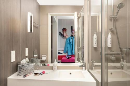 a bathroom with a sink and a woman in a mirror at Moxy London Excel in London