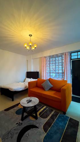 un soggiorno con divano arancione e letto di Pamsal Studio a Thika