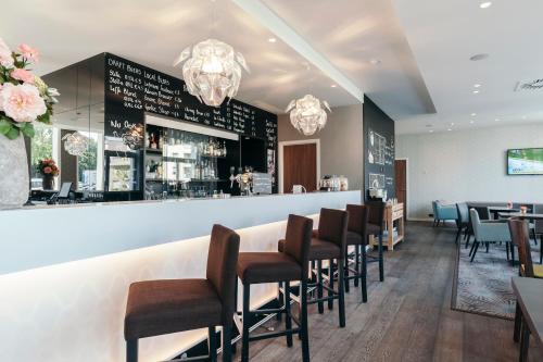 a restaurant with a bar with chairs and tables at Leopold Hotel Oudenaarde in Oudenaarde