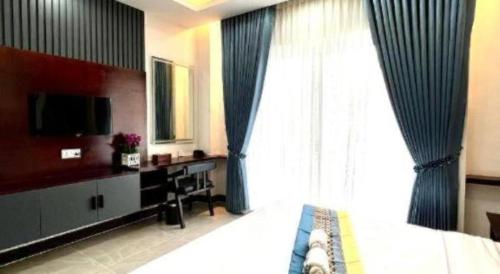 Phumĭ Bœ̆ng Phlŏng (2)Sky Boutique Kampot的一间带床、电视和窗户的卧室