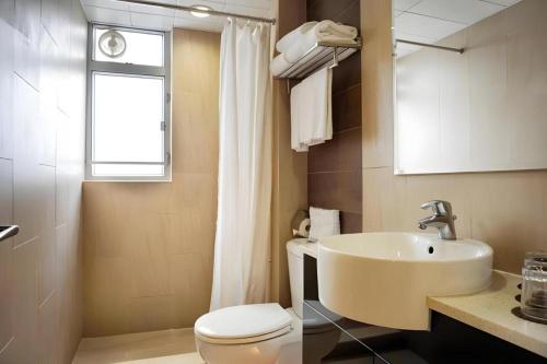ein Badezimmer mit Waschbecken und Toilette und einem Fenster in der Unterkunft H1 Hotel in Hongkong