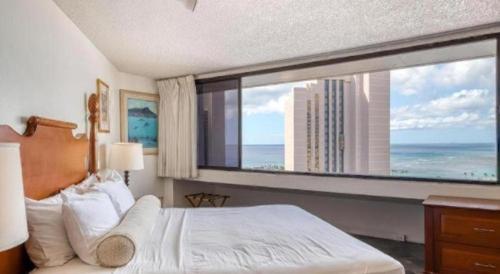 una camera da letto con una grande finestra con vista sull'oceano di Marina Tower Waikiki a Honolulu