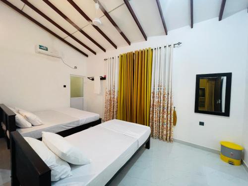 a bedroom with two beds and a yellow curtain at Coco Villa Yala in Tissamaharama