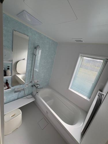 a bathroom with a tub and a sink and a window at 里山のいぶき舎 in Goto