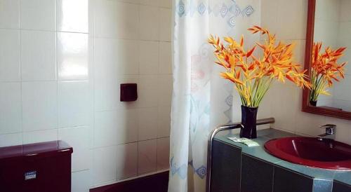 baño con lavabo y jarrón con flores en Global Hotel Labuan, en Victoria Town