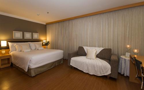 a hotel room with two beds and a chair at Transamerica Executive Jardins in Sao Paulo