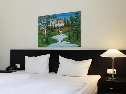 un cuadro sobre una cama en una habitación de hotel en Aariana Hotel en Offenbach