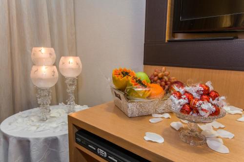 a table with two candles and a bowl of fruit at Transamerica Executive Jardins in Sao Paulo