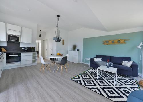 a living room with a blue couch and a kitchen at Strandperle in Juliusruh