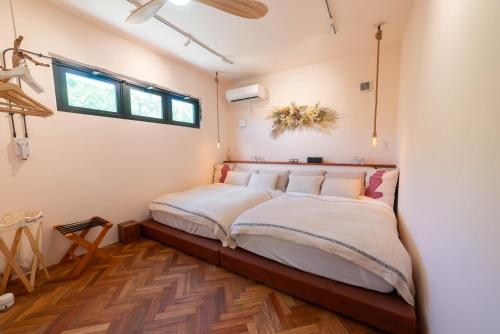 a bedroom with a bed with white sheets and a window at The House By The Sea in Miyako-jima
