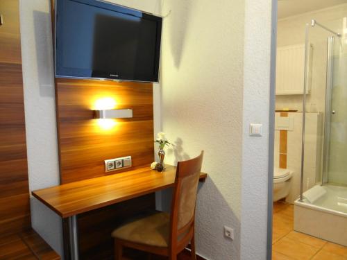 a room with a desk with a television on a wall at Hotel Schützenhof SPA GARDEN in Bürstadt