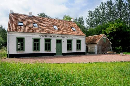 a white building with a red roof and a table at 't Schippershuis in Vurste