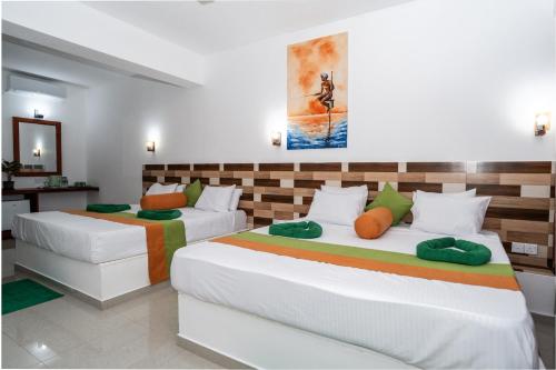 two beds in a hotel room with at Serenade Beach Hotel in Hikkaduwa
