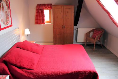 ein Schlafzimmer mit einem roten Bett und einem Stuhl in der Unterkunft Gîte Sylvaner sur la route des vins in Kintzheim