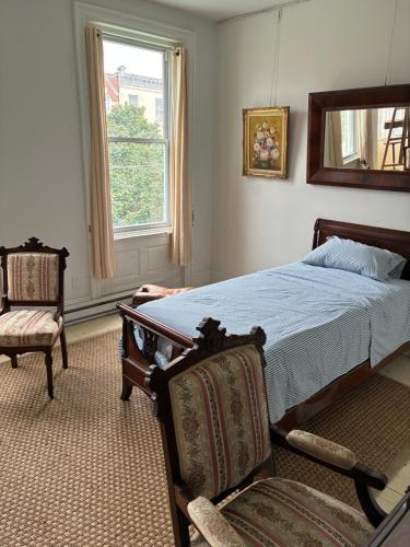 a bedroom with a bed and two chairs and a window at Gilded Age Tower in Philadelphia
