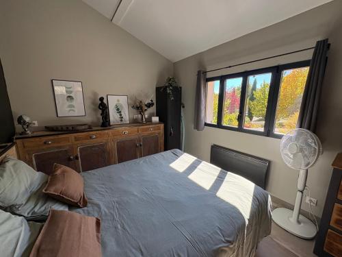 a bedroom with a bed with a fan and a window at Pigeonnier des Banons in Puimoisson