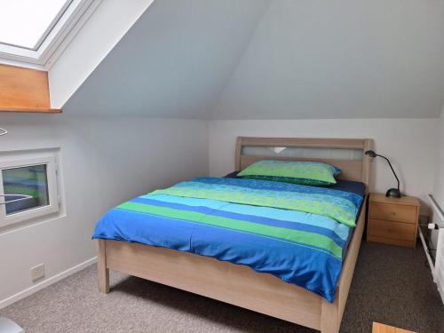 Schlafzimmer mit einem Bett mit einer blauen und grünen Bettdecke in der Unterkunft Dachwohnung in Niederuzwil
