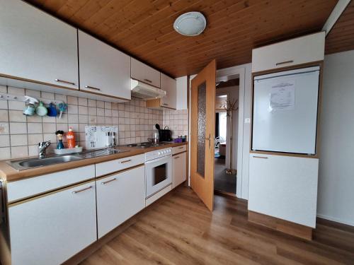 eine Küche mit weißen Schränken und einem weißen Kühlschrank in der Unterkunft Dachwohnung in Niederuzwil