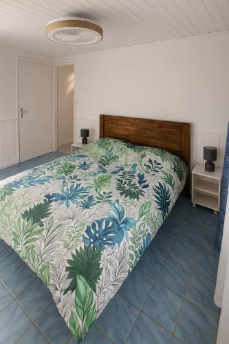 a bedroom with a bed with a floral bedspread at KaZen chez Steph in Petite Île