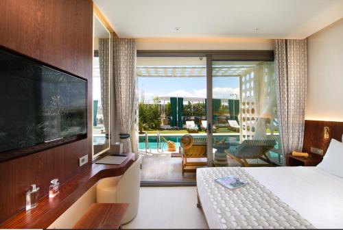 ein Schlafzimmer mit Bett, Fernseher und Balkon in der Unterkunft The Xon Hotel in Cesme