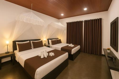 a bedroom with two beds and a television at EMERALD HAVEN SAFARI Cottages in Udawalawe