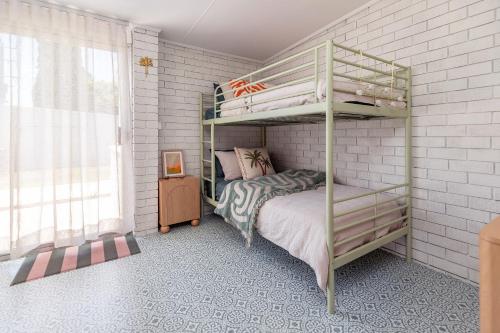 Un dormitorio con literas en una pared de ladrillo blanco. en Sunset Sisters - Villa Lola & Villa Frankie, en Forster