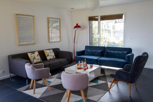 a living room with a couch and chairs and a table at Jolie maison neuve PMR au port de l'Aberwrac'h in Landéda