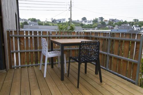 einen Holztisch und zwei Stühle auf einer Terrasse in der Unterkunft Jolie maison neuve PMR au port de l'Aberwrac'h in Landéda