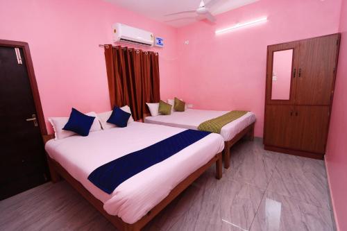 Arun Auro Residency في Kuilapayam: سريرين في غرفة بجدران وردية