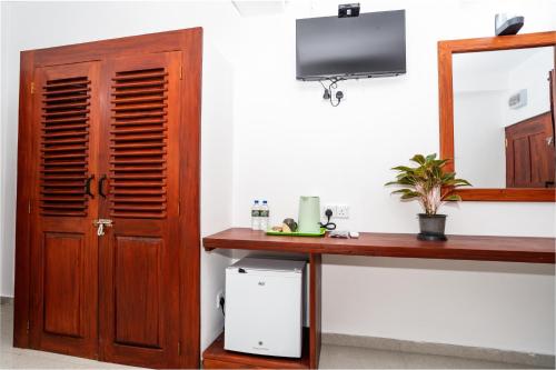 a room with a table and a mirror and a television at Serenade Beach Hotel in Hikkaduwa