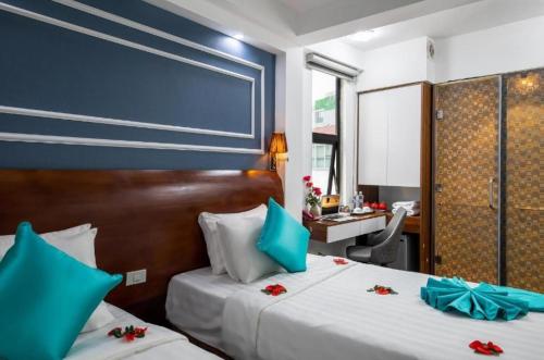 a bedroom with two beds and a desk in a room at Hanoi Cozy Boutique Hotel in Hanoi