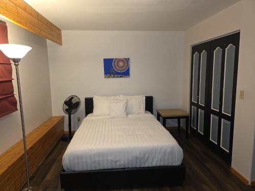 a bedroom with a bed with white sheets and a lamp at Bujaks in Inuvik