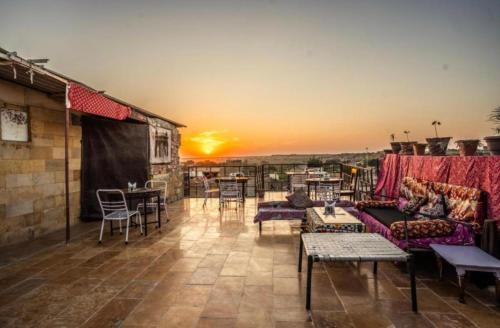 Hotel Al-raya Jaisalmer في جيلسامر: بلكونه مع كنب وطاولات وغروب الشمس