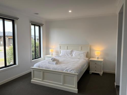 a bedroom with a white bed and two windows at Stunning 4 X Bed Holiday Home In Kalkallo! in Kalkallo