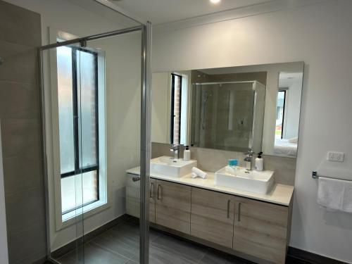a bathroom with two sinks and a mirror at Stunning 4 X Bed Holiday Home In Kalkallo! in Kalkallo