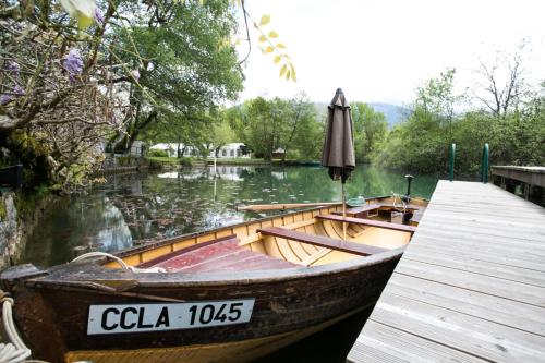 una barca parcheggiata accanto a un molo con un ombrellone di Les Nénuphars magnifique villa au bord du canal a Saint-Alban-de-Montbel
