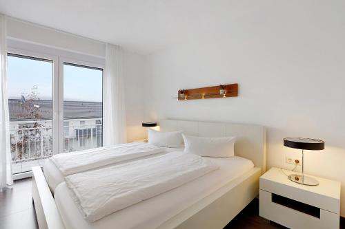 赫汀恩Markgraf Apartments Haus 5的一间白色的卧室，有一张白色的大床和一扇窗户