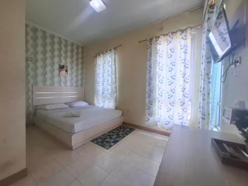 1 dormitorio con 1 cama en una habitación con cortinas en Tamastu Hotel Fortuna Jatiwaringin, en Pangkalan