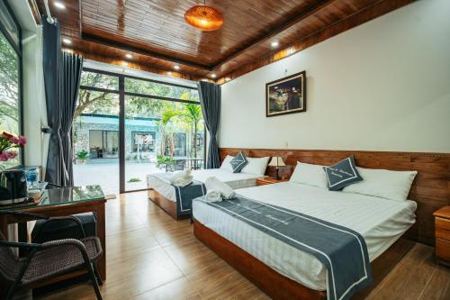 Un dormitorio con dos camas y un escritorio y una ventana. en Tràng An Riverbank Homestay, en Nguyên Ngoại