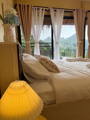 a bedroom with a bed with a large window at บ้านสวนผาหมี in Ban Nong Chaeng